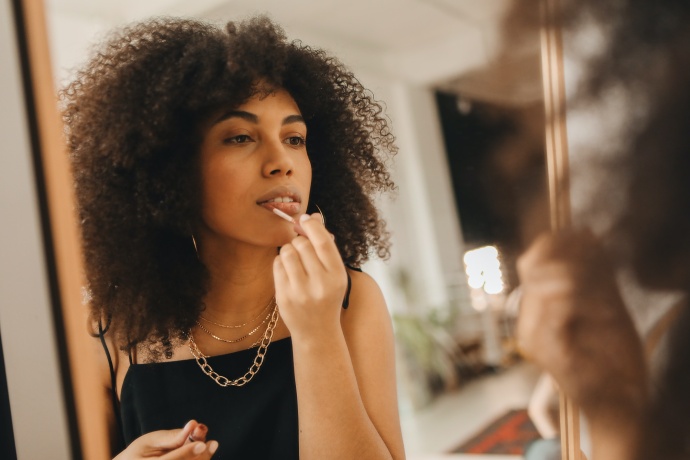 Mulher jovem a maquilhar-se ao espelho