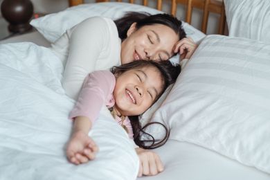 Mãe e filha a dormir sorridentes